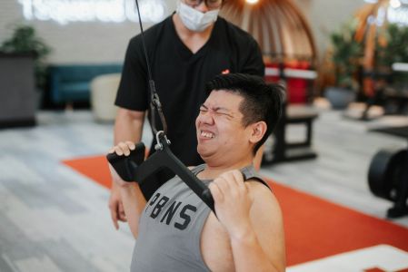 Man straining while doing a cable pull exercise.