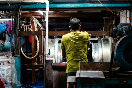 Man working in a laundry facility with large machines.